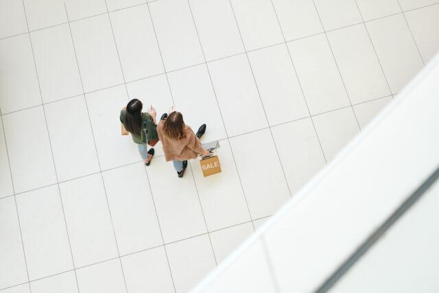 Above view of young women with shopping bags walking together over mall